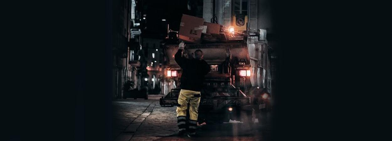 camião de recolha de lixo em rua escura