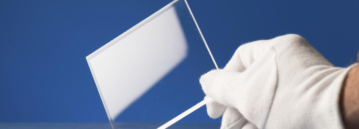 mão com luva branca a segurar quadrado de vidro temperado