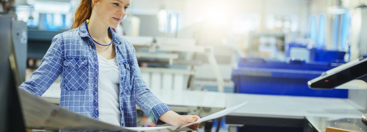 mulher segura páginas junto a máquina de impressão