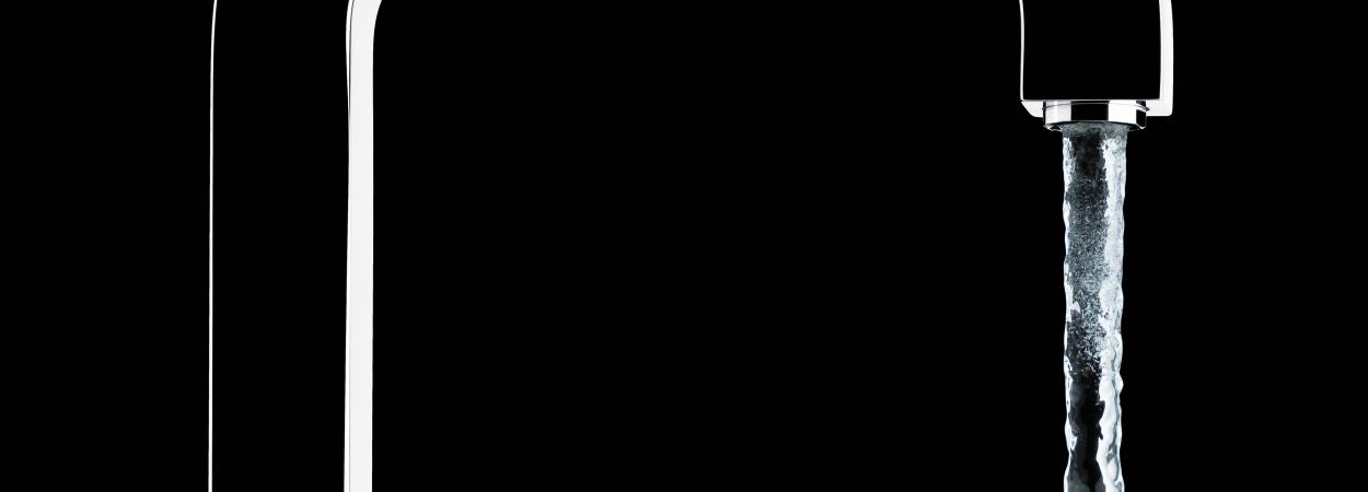 água a correr de torneira em fundo negro 