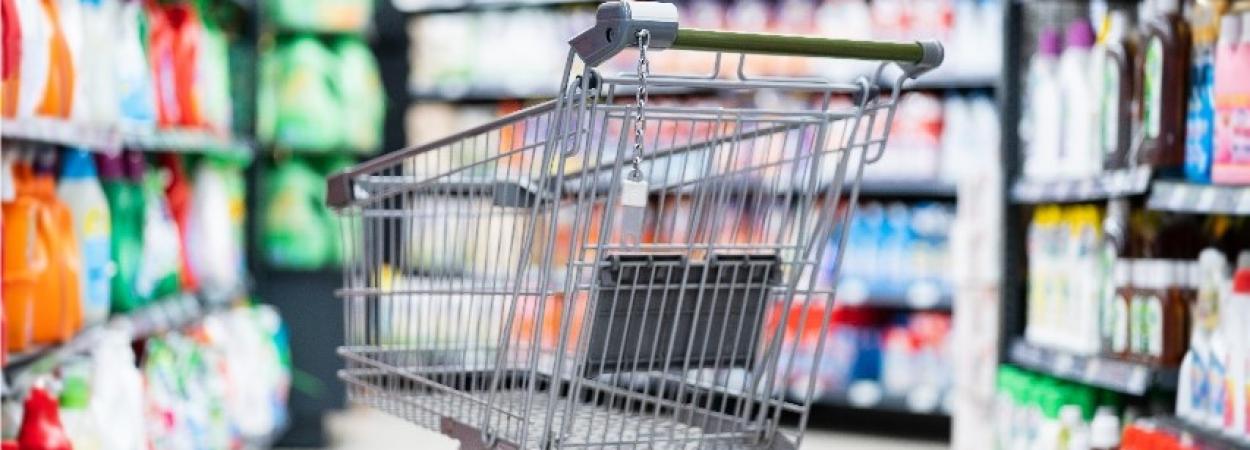 carrinho de compras vazio em corredor de supermercado com produtos de limpeza