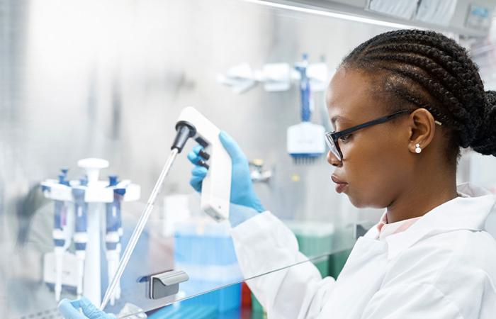 Mulher de bata branca manuseando utensílios de laboratório de biotecnologia