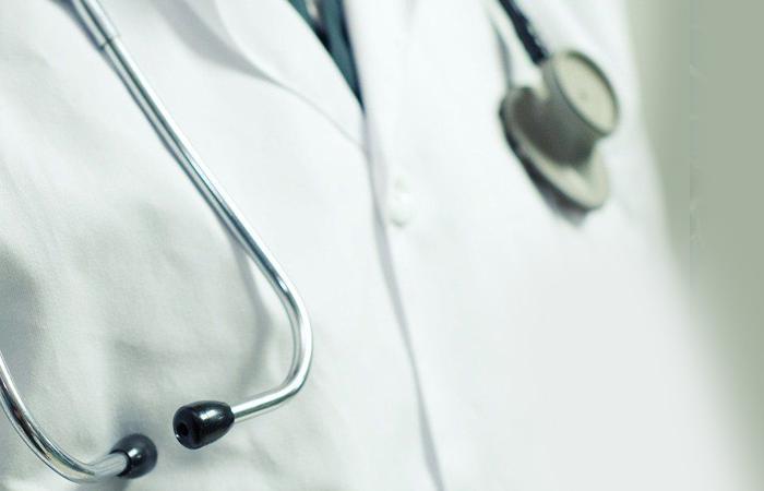 torso de homem com bata branca usando estetoscópio ao pescoço