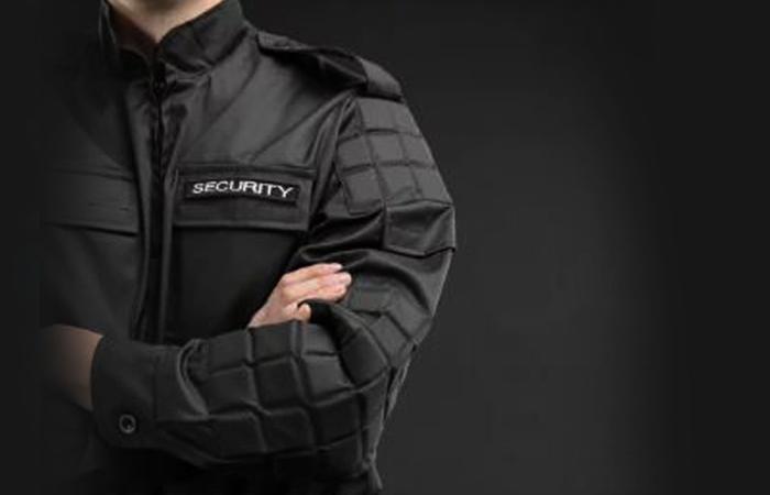 fundo negro com homem usando blusão identificado com a palavra security