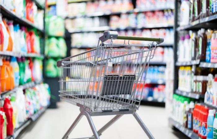 carrinho de compras vazio em corredor de supermercado com produtos de limpeza