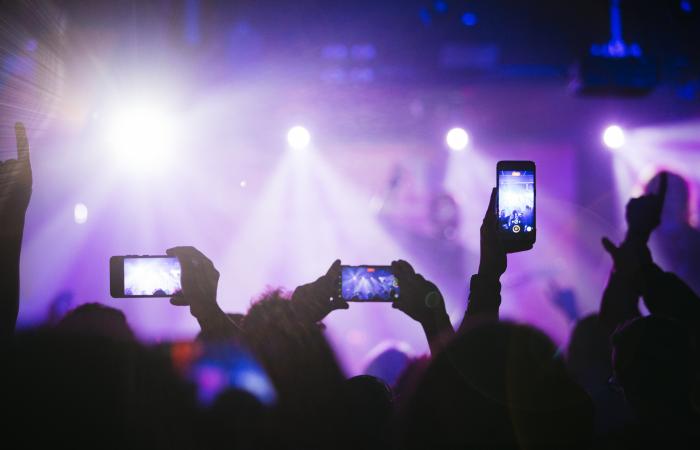 pessoas empunham telemóveis em espetáculo