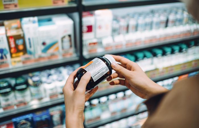 mãos de mulher a manusear um frasco de suplemento alimentar