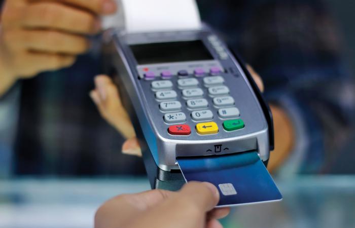 mãos a segurarem terminal de pagamento e cartão