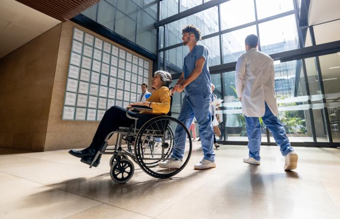 mulher em cadeira de rodas em átrio de hospital
